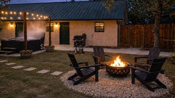 Un patio trasero con una chimenea, asientos exteriores y una parrilla de barbacoa.