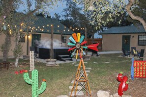 Un jardin avec un moulin à vent, un cactus, une échelle en métal et un jacuzzi.