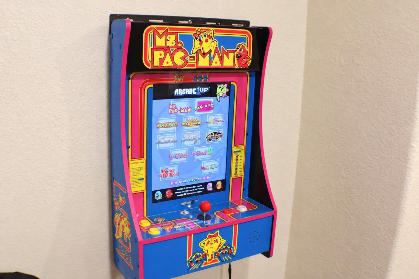 Une borne d’arcade ancienne, dotée d’un design coloré et proposant une sélection de jeux.