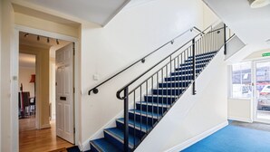 Una scala con gradini rivestiti di tappeto blu e ringhiere nere, che conduce a un piano superiore.