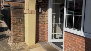 Un edificio residenziale con facciata in mattoni, un'ampia porta in vetro e un piccolo portico.