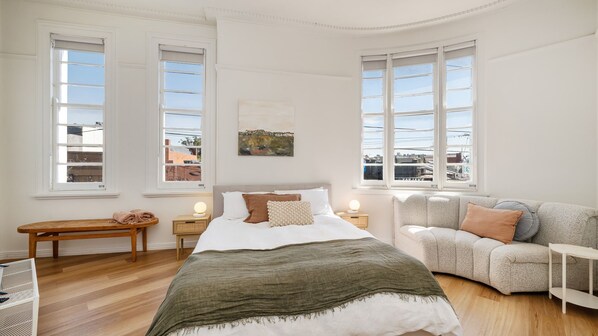 A bedroom with a large bed, a sofa, a bench, and two bedside tables with lamps. - The Barkly Scene with Rooftop Retreat (St Kilda)