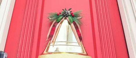 A red door with a golden bell and a wreath, above which is a sign reading "Noble Loft".