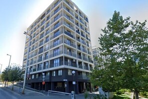 Un immeuble à plusieurs étages doté d’une architecture moderne, avec des balcons et un toit plat.