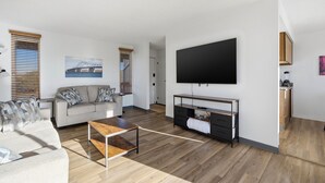 Ein modernes Wohnzimmer mit Sofa, Couchtisch, Fernseher und Holzboden.