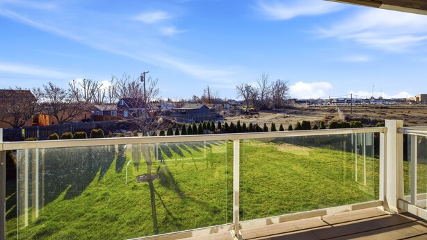 Ein Balkon mit Blick auf ein grünes Feld und entfernte Gebäude.
