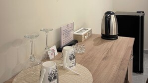 Une chambre d’hôtel équipée d’un téléviseur à écran plat fixé au mur, d’une table en bois avec une machine à café, une bouilloire et un présentoir de menus.