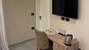 Une chambre d’hôtel équipée d’un bureau, d’une chaise, d’une télévision et d’un mini-bar.