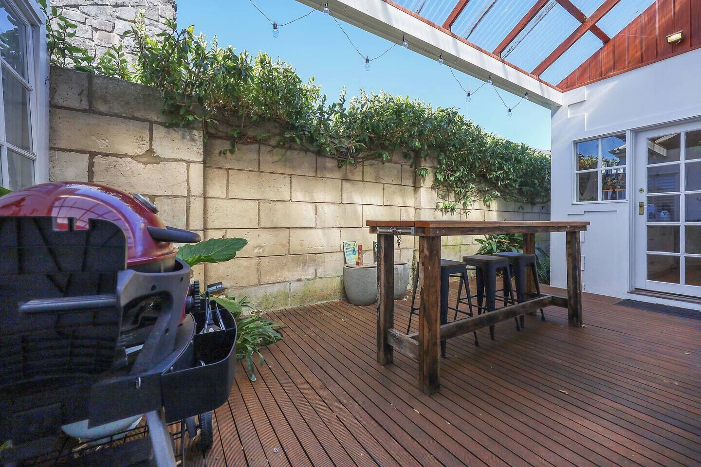 Una terraza de madera con una parrilla, una mesa y sillas.