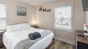 A bedroom with a bed, a nightstand, a lamp, and artwork on the walls.