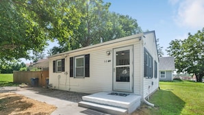 A single-story mobile home with a front porch, a garage, and a small backyard.