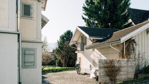 Une maison d’habitation avec une allée gravillonnée, un vélo et une chaise blanche à l’extérieur.