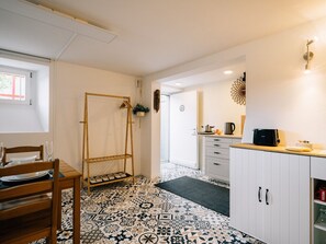 A compact kitchen with white cabinets, a wooden dining table, and a patterned floor. - Urban Studio directly at Spiez train station (Spiez)