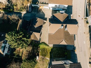 Vista aérea de una zona residencial con varias casas, una carretera y un gran árbol.