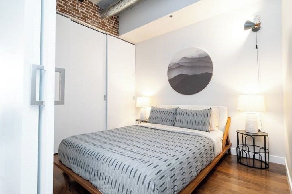 A bedroom with a bed, a round wall art, a nightstand, and a lamp.