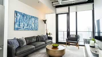 A modern living room with a grey sofa, a round coffee table, and a large abstract painting on the wall.
