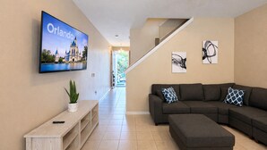Una sala de estar moderna con un sofá modular, un televisor de pantalla plana y obras de arte en las paredes.