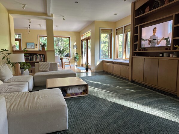 A living room with a sofa, a coffee table, a television, and a bookshelf.