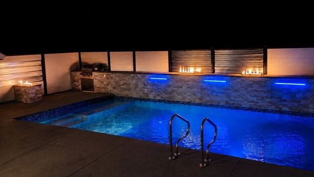 Una piscina con pared de piedra y una chimenea integrada.