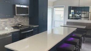 Una cocina moderna con armarios oscuros, una isla grande y taburetes de bar.