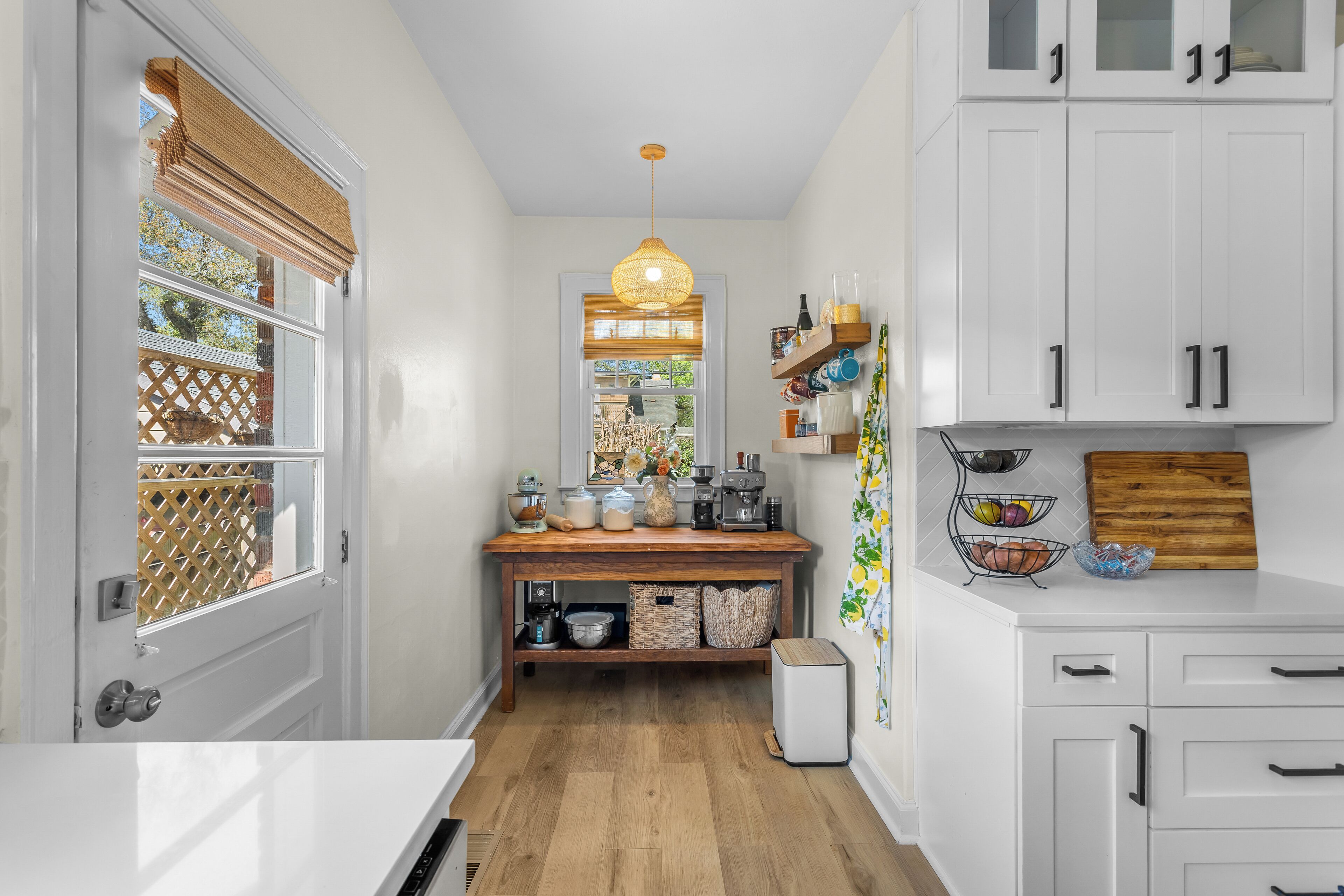 A kitchen with white cabinets, a wooden countertop, and a hanging light fixture.