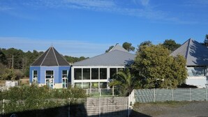 Een modern gebouw met een schuin dak, grote ramen en een omheind gebied ervoor.