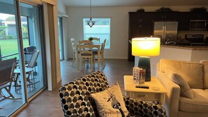 A living room with a patterned armchair, a table with a lamp, and a sofa. - GORGEOUS 3-bedroom house with NEW golf cart in The Villages! Perfect location! (The Villages)