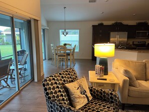 Ein Wohnzimmer mit einem gemusterten Sessel, einem Tisch mit Lampe und einem Sofa.