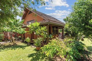 Une maison de plain-pied, dotée d’un toit en tuiles, entourée d’une végétation luxuriante et d’une pelouse bien entretenue.