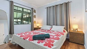 Ein Hotelzimmer mit Bett, zwei Nachttischen mit Lampen, einem Fenster mit Vorhängen und einer Tür.
