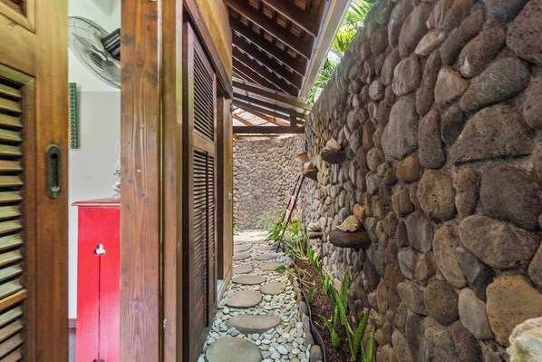 A narrow stone pathway leading to a wooden door with a red mailbox.