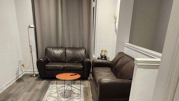 Una sala moderna con un sofá de cuero marrón, una mesita de centro naranja y una alfombra estampada.