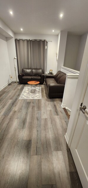 Ein modernes Wohnzimmer mit einer braunen Ledersofa, einem kleinen orangefarbenen Couchtisch und einem gemusterten Teppich.