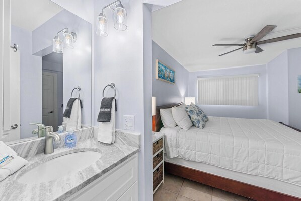 A bedroom with a bed, a ceiling fan, a nightstand, and a mirror.