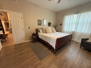 A bedroom with a wooden bed, a bedside table, a chair, and a window with curtains. - Poga Ranch- Lake Istokpoga, Private Dock, pool, Sunsets, Lake Placid, FL (Lorida)