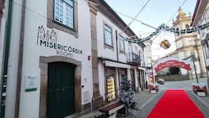 A building with a sign for "MISERICÓRDA ROOMS" and a red carpet leading to a building entrance. - Misericordia Rooms (Guarda)