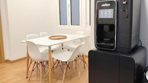A compact room with a white table and chairs, a water dispenser, and a small refrigerator. - Misericordia Rooms (Guarda)