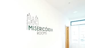 A wall with a logo for 'MISERICÓRDIA ROOMS' and a wooden floor. - Misericordia Rooms (Guarda)