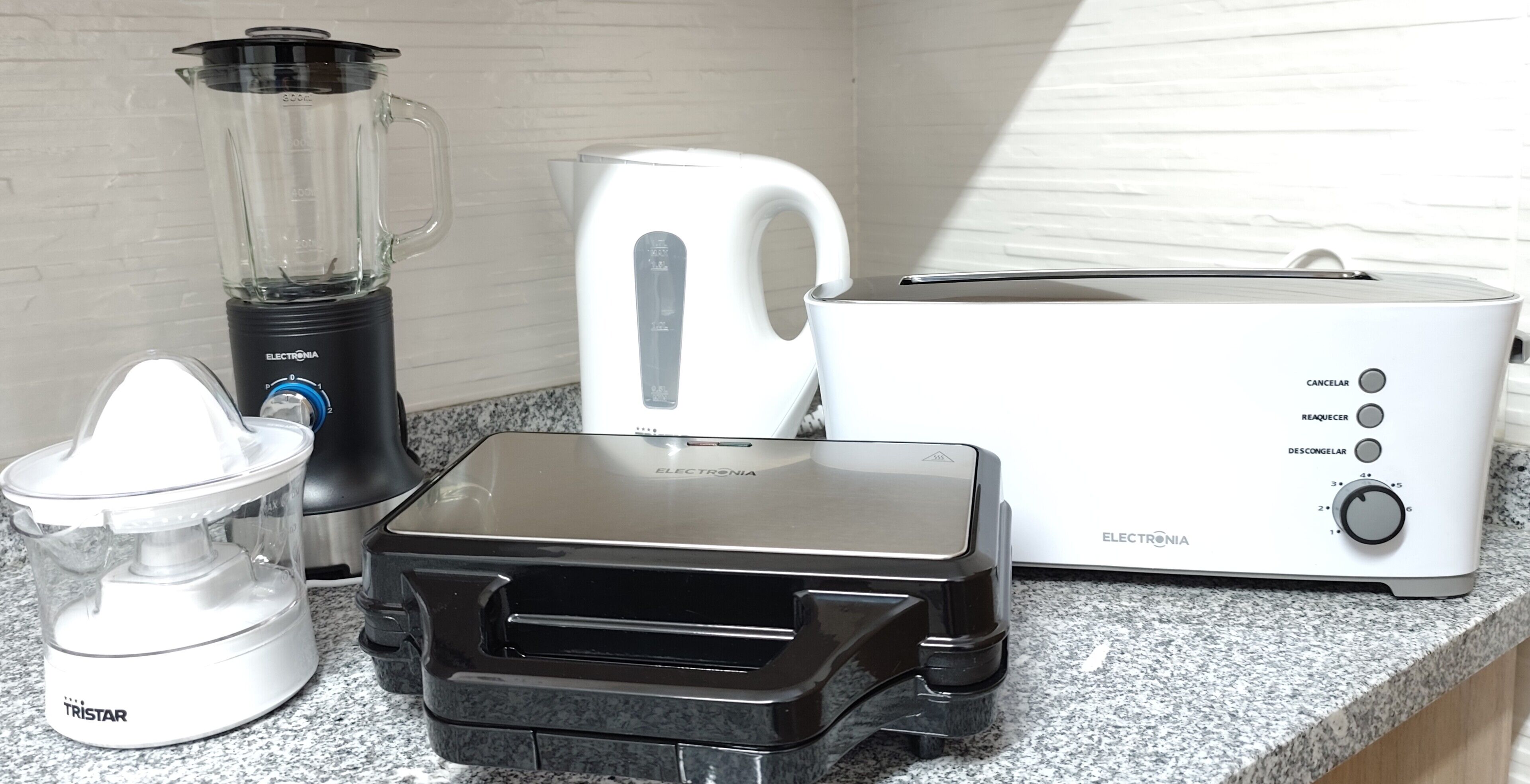 Een keuken met een blender, toaster en waterkoker op een granieten aanrecht.