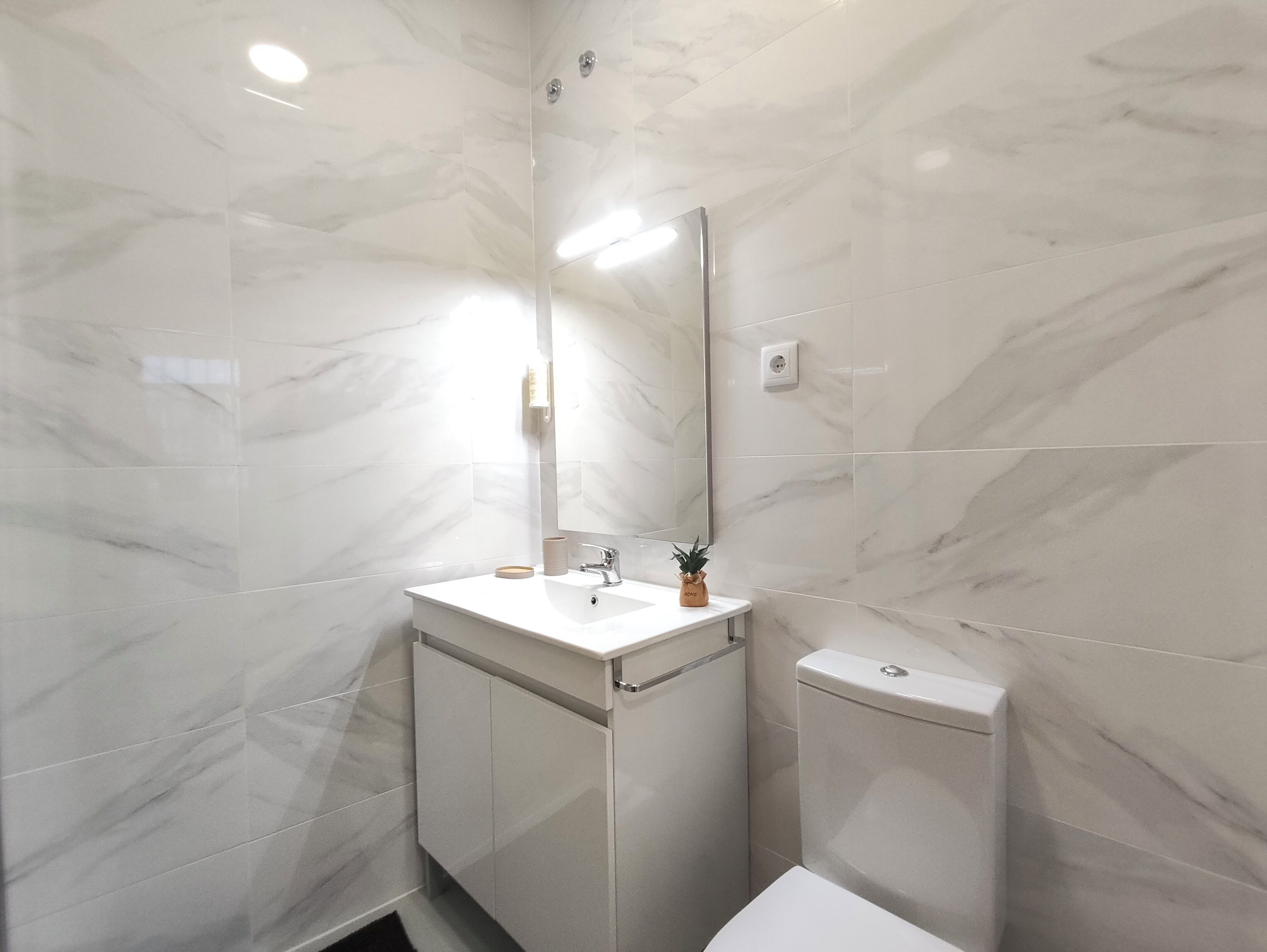 A bathroom with a white marble sink, a mirror, and a toilet.