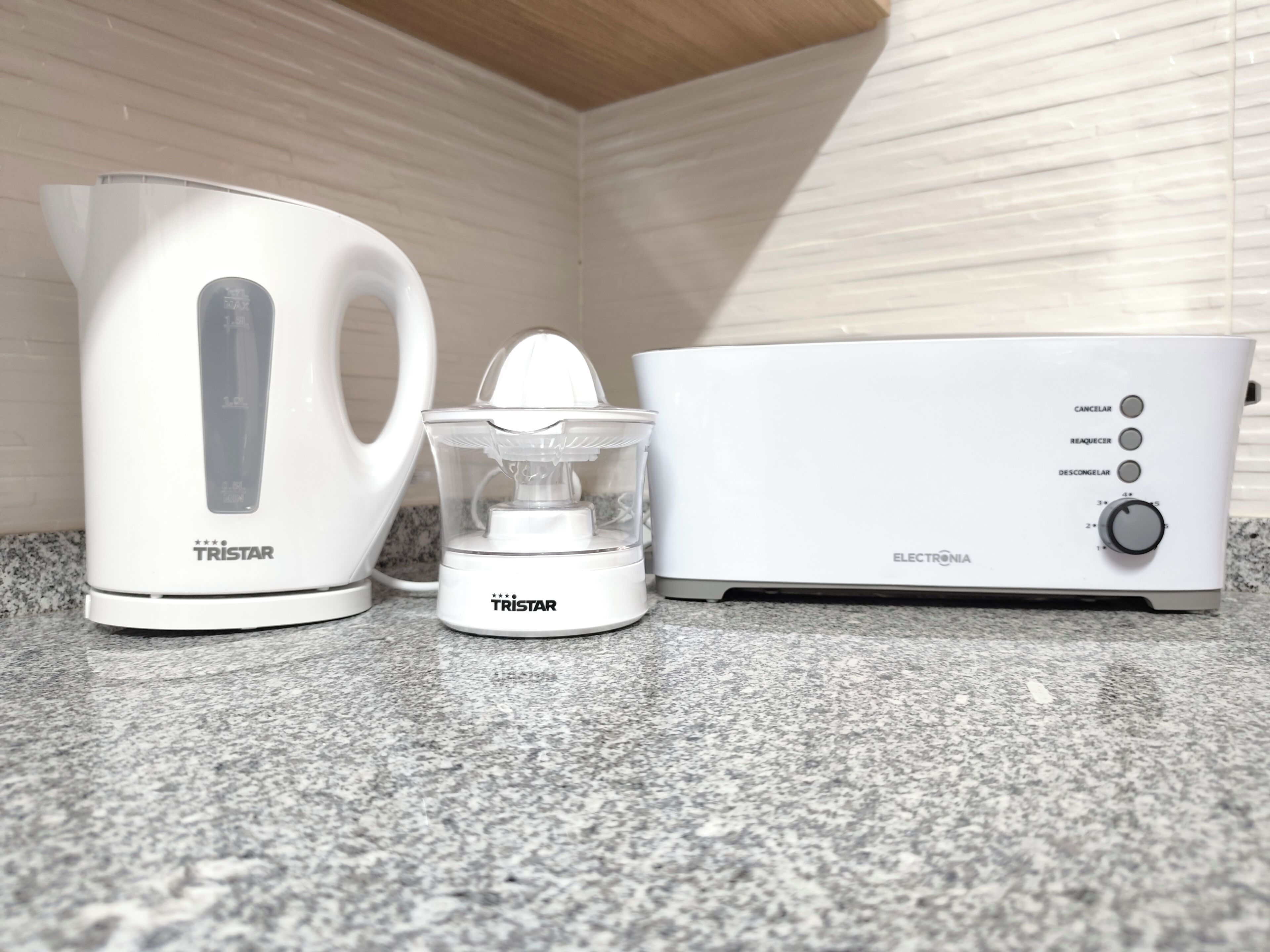 Eine Küche mit einem weißen Wasserkocher, einem Entsafter und einem Toaster.