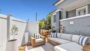 A patio with wicker furniture, a white potted plant, and a grey building in the background.