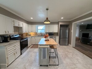 A modern kitchen with white cabinetry, a central island, stainless steel appliances, and a pendant light. - Pecan Grove | Spacious South Abilene Stay (Abilene)