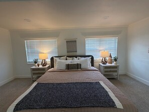 A bedroom with a bed, two bedside tables, and two lamps.