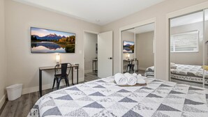 A bedroom with a large bed, a desk, a chair, a mirror, and a painting of a mountain landscape. - UO•Downtown(.5 mile)•West University•GuestFavorite (Eugene)