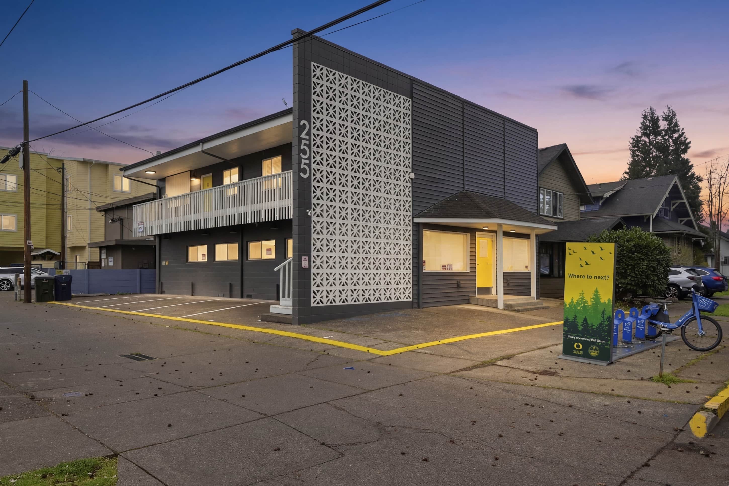 A modern building with a balcony, a parking area, and a bicycle parking sign.