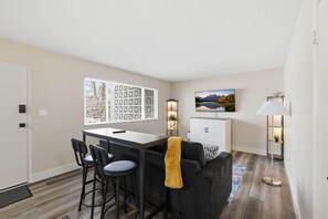 Un salon moderne comprenant un coin repas, un canapé, un téléviseur et une lampe.