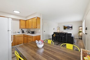 A modern kitchen with wooden cabinets, a dining table with chairs, and a living area with a couch and chairs. - UO•Downtown (1/2 mile)•West University•King Suite (Eugene)