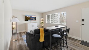 A modern kitchen with a dining area, a sofa, a bar stool, and a lamp. - UO•Downtown (1/2 mile)•West University•King Suite (Eugene)
