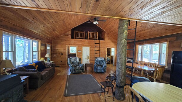 Ein Interieur einer Hütte mit Holzdielen, einem Essbereich und einem Wohnzimmer mit Sofa und Sesseln.